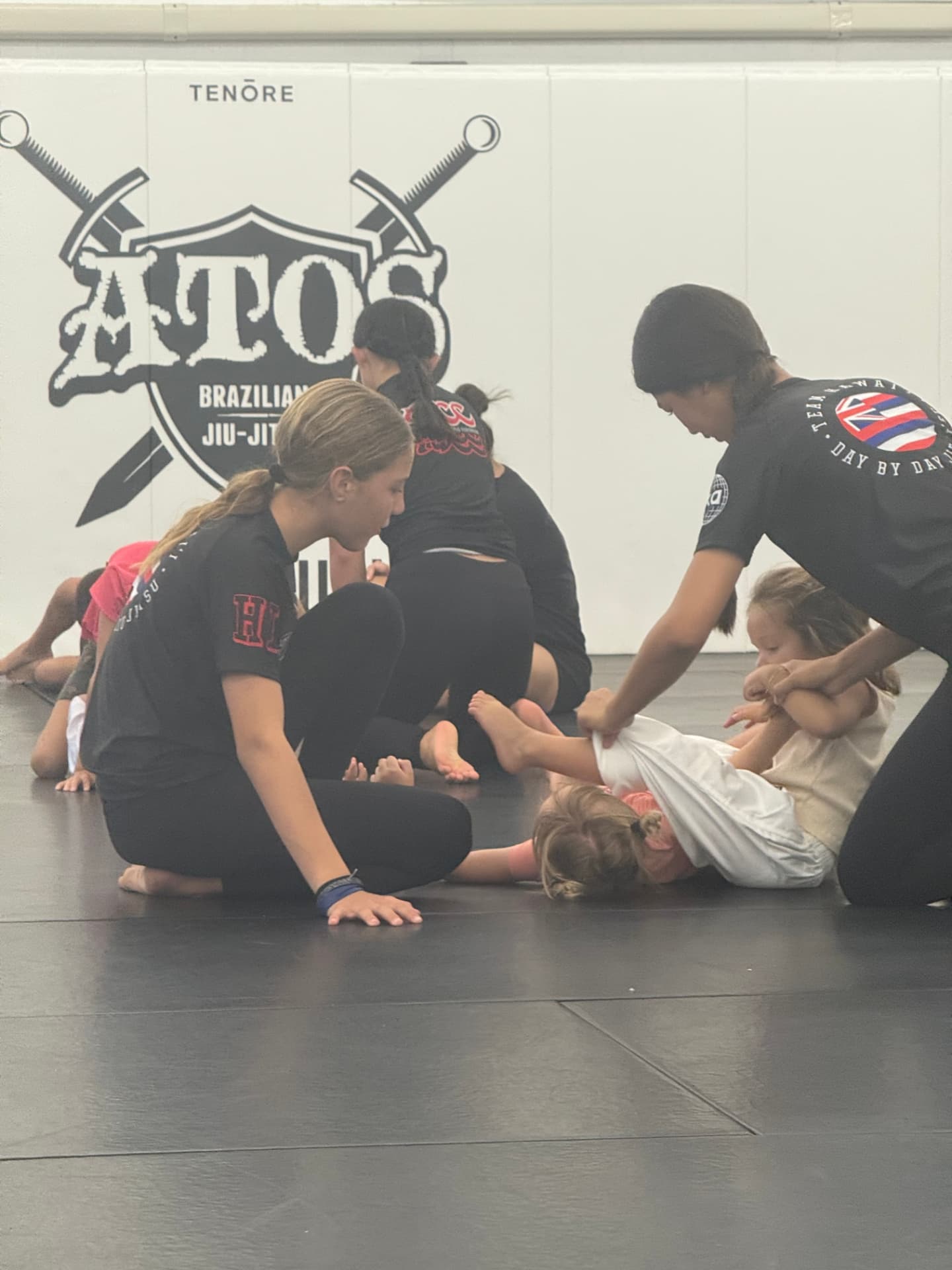 Coaches teaching young kids technique on the mats