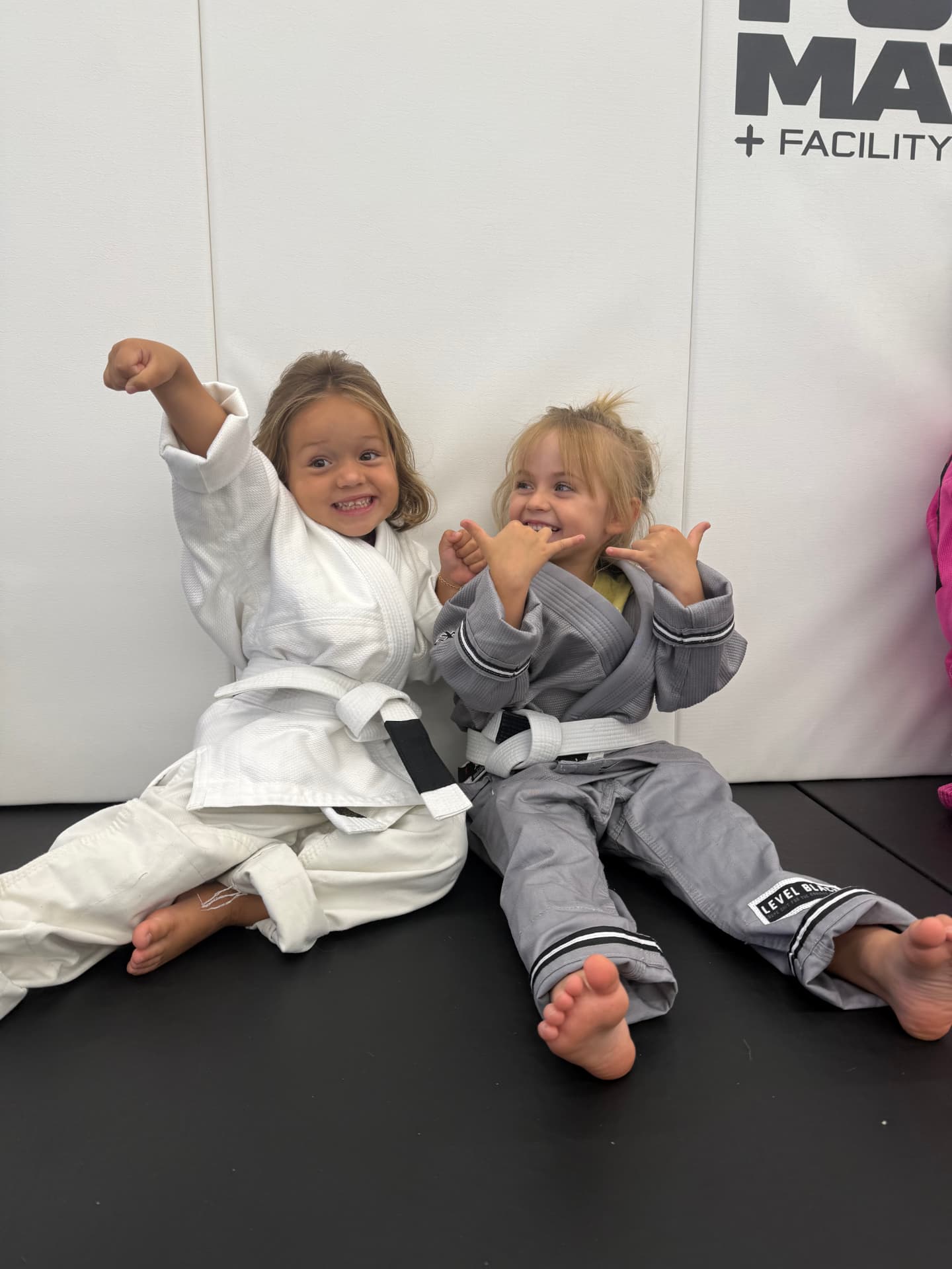 Two young students in gis throwing shakas after class